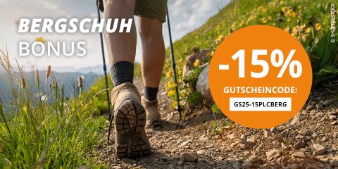 Eine Person wandert in Wanderausrüstung und Rucksack einen felsigen Bergpfad hinauf. Der Text auf dem Bild erwähnt „BERGSCHUH BONUS“, „-15% GUTSCHEINCODE: GS25-15PLCBERG“. Im Hintergrund sind ein bewölkter Himmel und felsige Gipfel zu sehen.