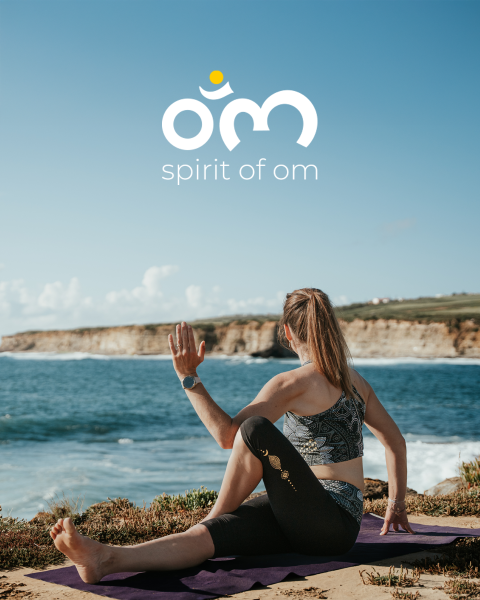 Eine Frau praktiziert Yoga am Meer, sitzt auf einer Matte und führt Drehübungen durch, während über ihr vor dem Hintergrund eines strahlend blauen Himmels der Schriftzug „Spirit of Om“ und ein Logo zu sehen sind.